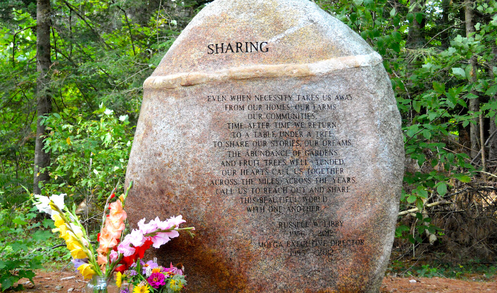 A stone with a poem engraved on it with two jars of flowers.