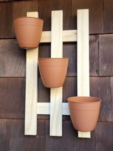 three plastic plant pots affixed to a wooden wall hanging