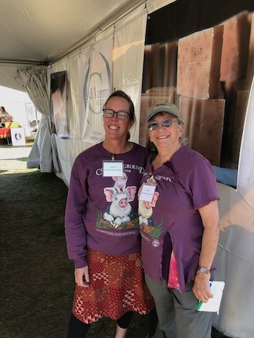 Two Common Ground Country Fair volunteers wear matching purple shirts with pig illustrations