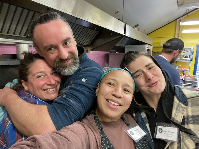 Four Common Ground Country Fair volunteers smile for a group selfie taken in MOFGA's Common Kitchen.