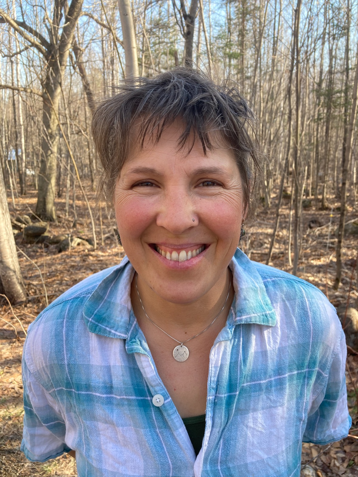 Volunteer Lisa Ravis smiles in the woods.